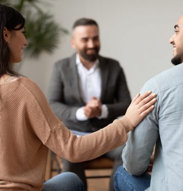 happy-couple-reconciling-at-therapy-session-in-therapists-office-e1625973671479